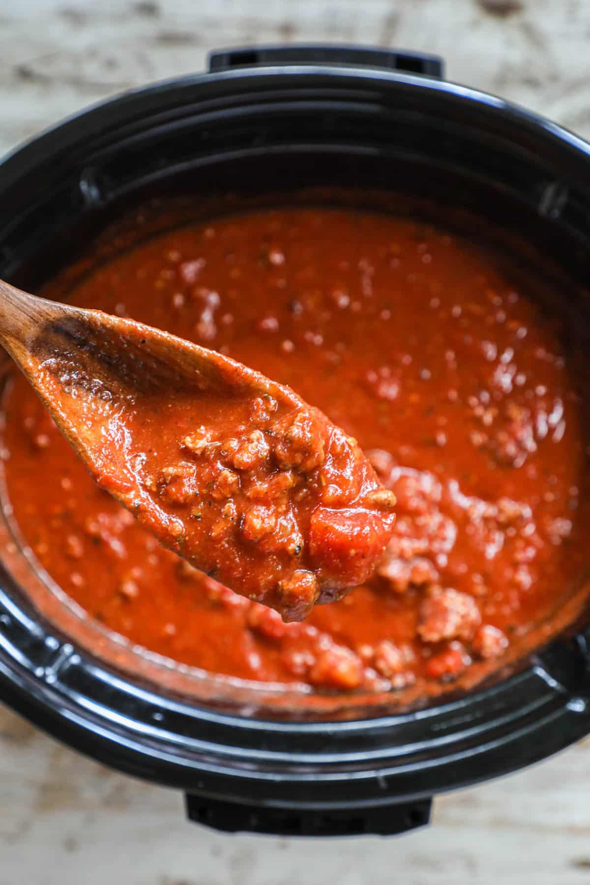 marinara sauce in a large stockpot with a wooden spoon.