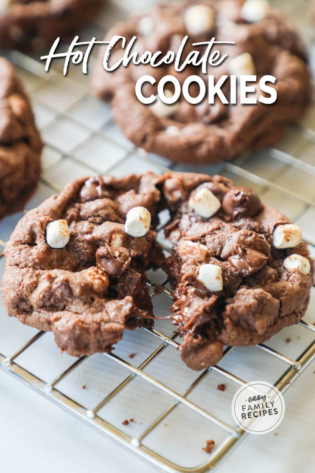 Hot chocolate cookies topped with mini marshmallows on a cooling rack.