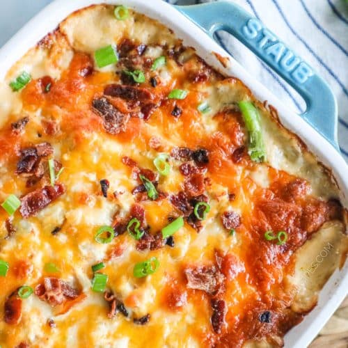 Partial top down view of cheesy casserole topped with crispy bacon and green onions.