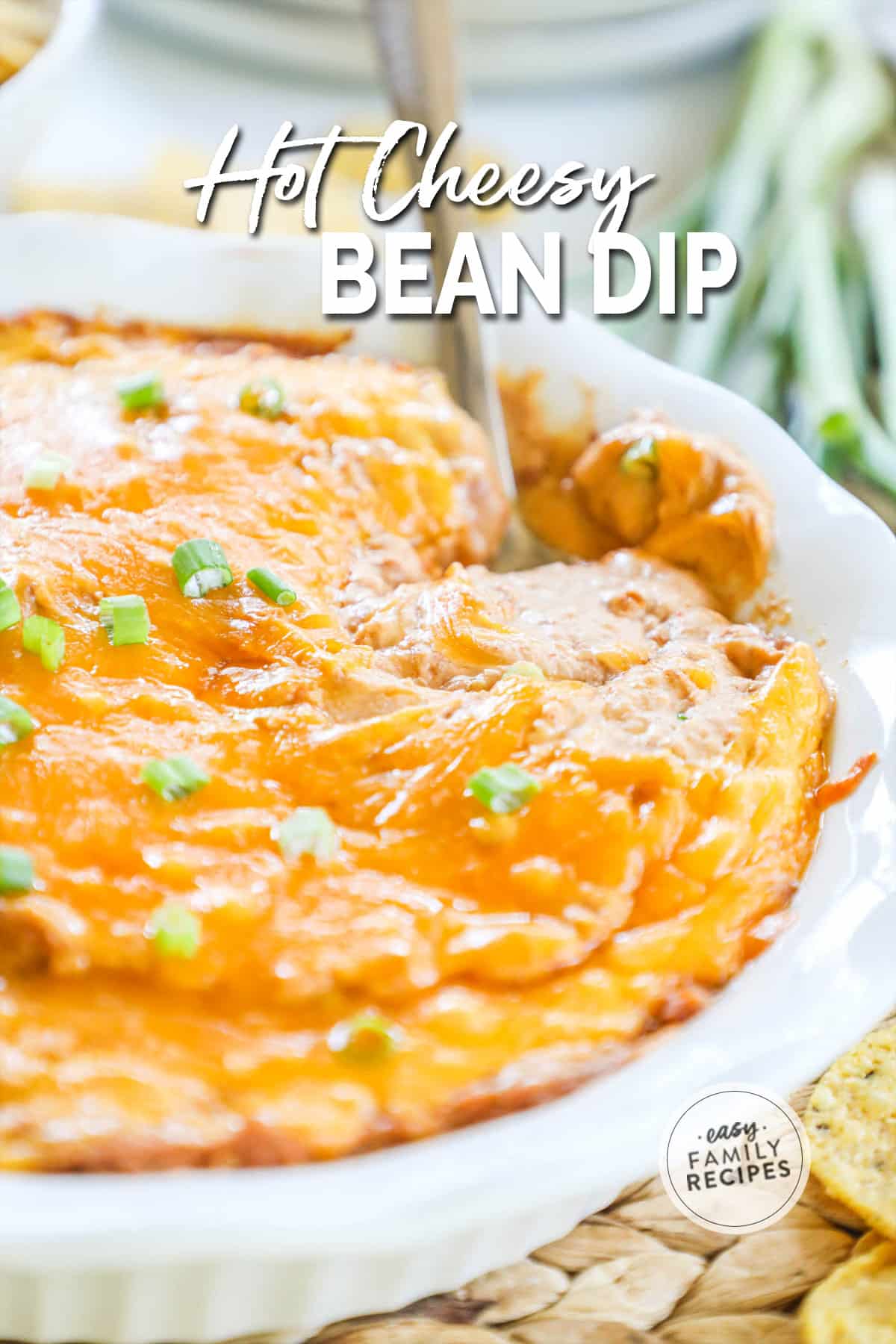 Cheesy bean dip in a casserole dish with a scoop taken out.