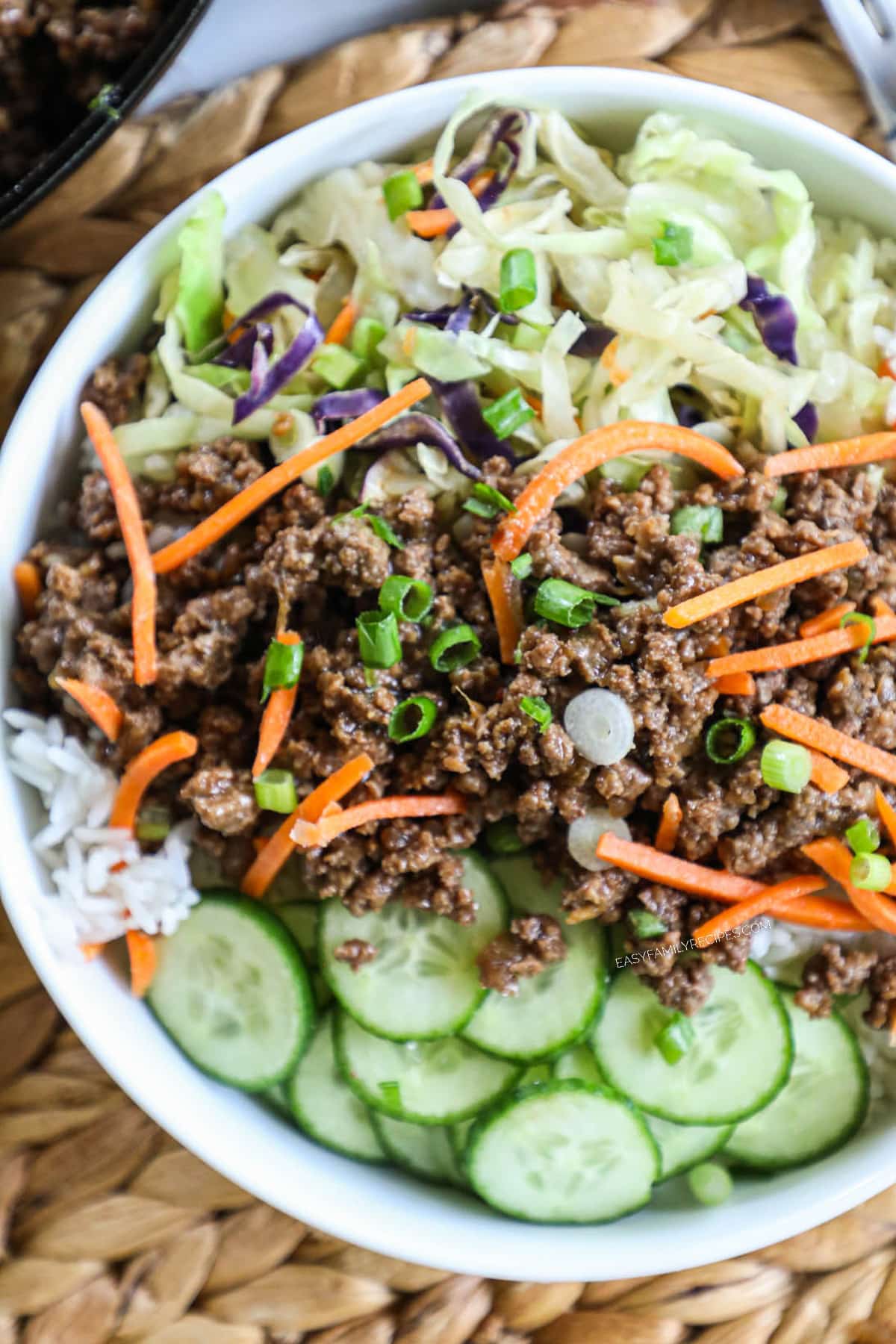 Overhead view of Korean Ground Beef Bowl with cucumbers , rice, cabbage and carrots.