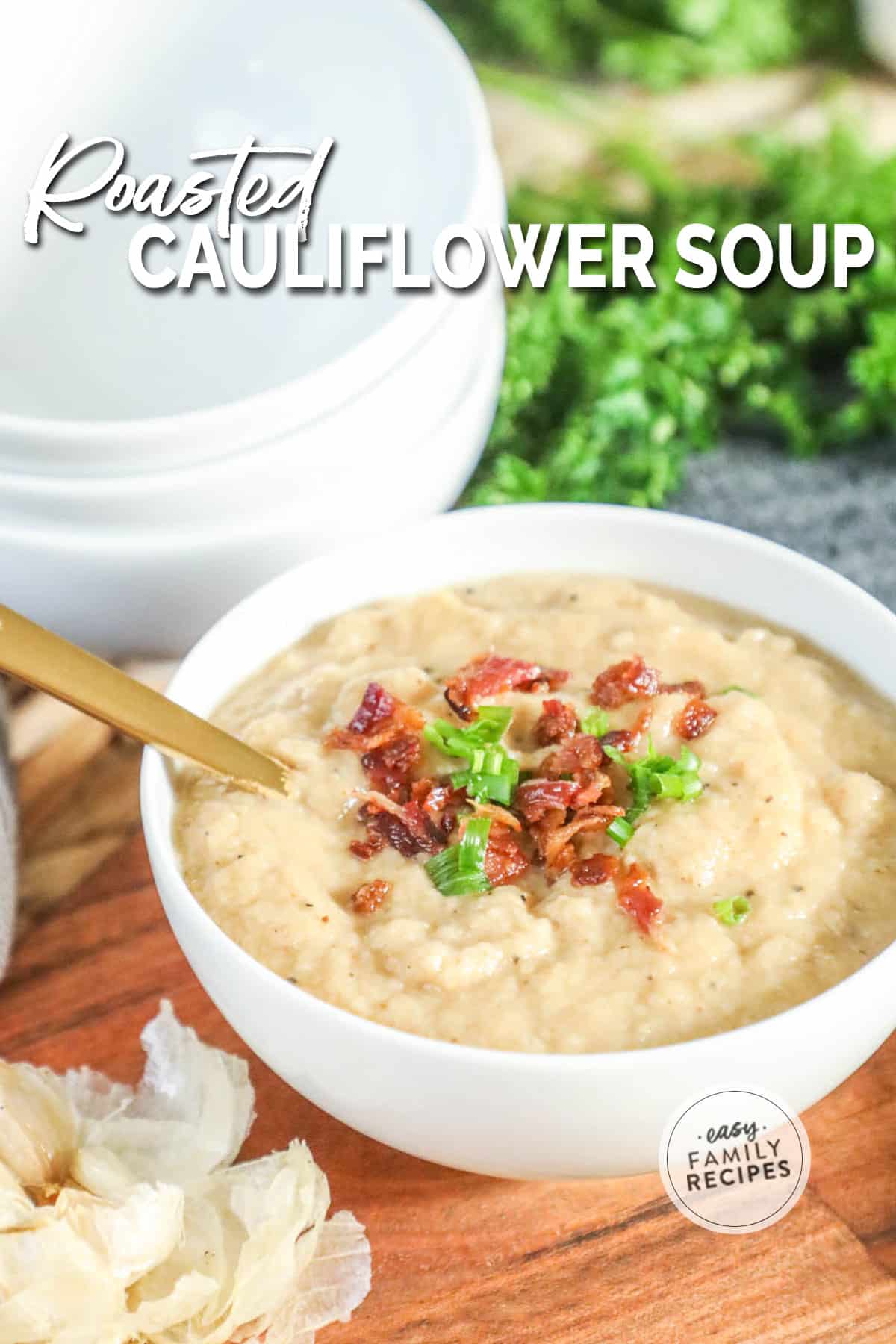 a white bowl filled with creamy roasted cauliflower soup topped with garnishes.
