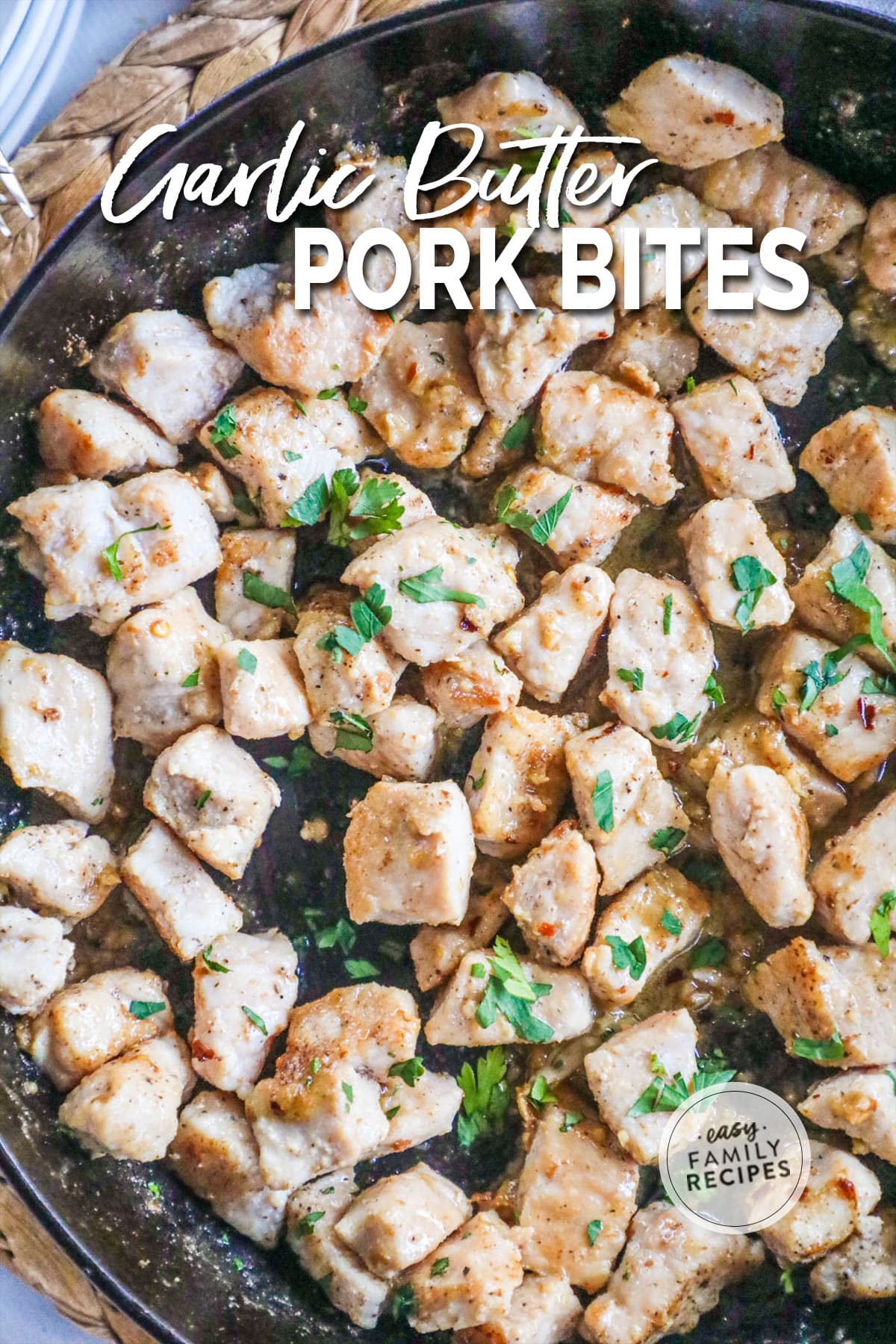 pork bites coated with garlic butter and sprinkled with parsley in a large pan.
