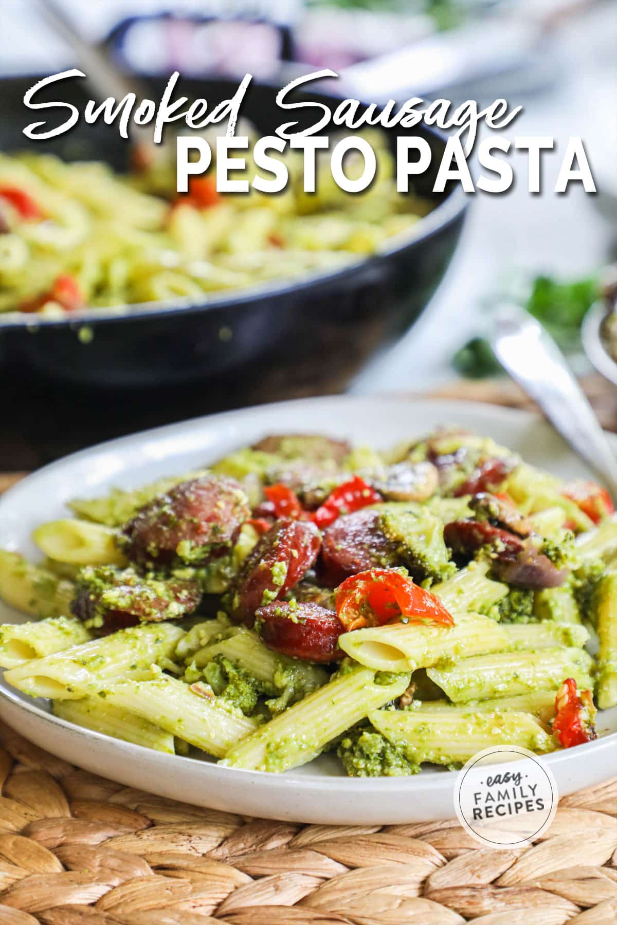 Completed smoked sausage and pesto pasta with veggies on a plate.