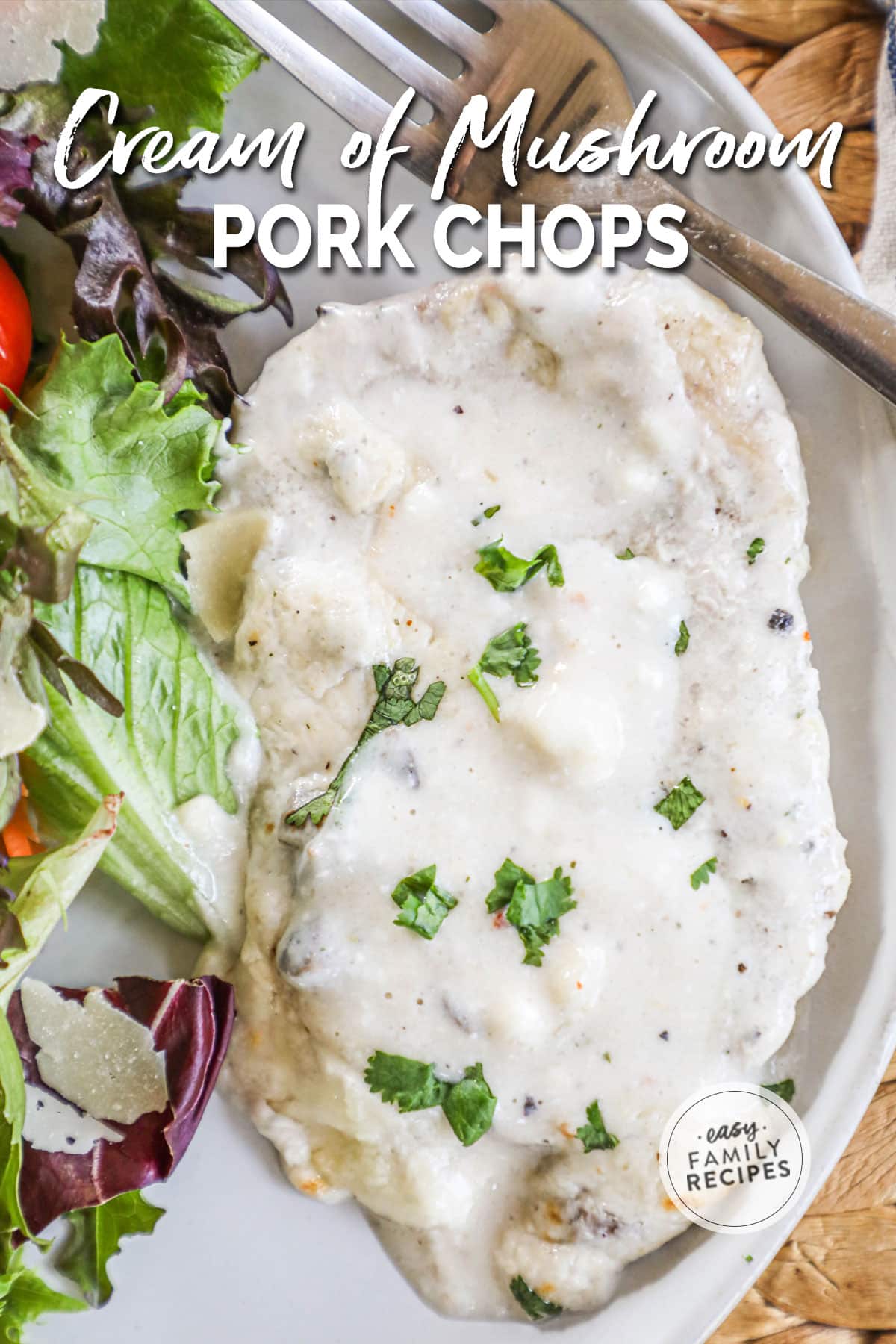 Baked cream of mushroom pork chop on a serving plate garnished with fresh herbs and plated with a fresh salad.