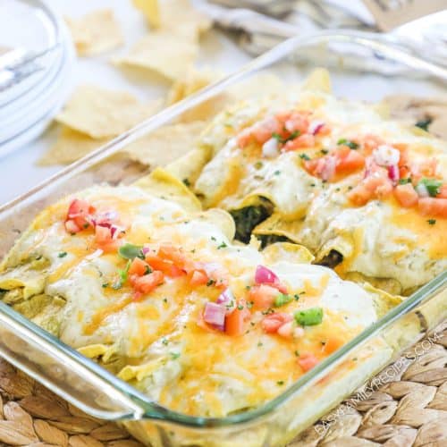 Enchiladas in a pan with golden brown cheese and topped with pico de gallo.