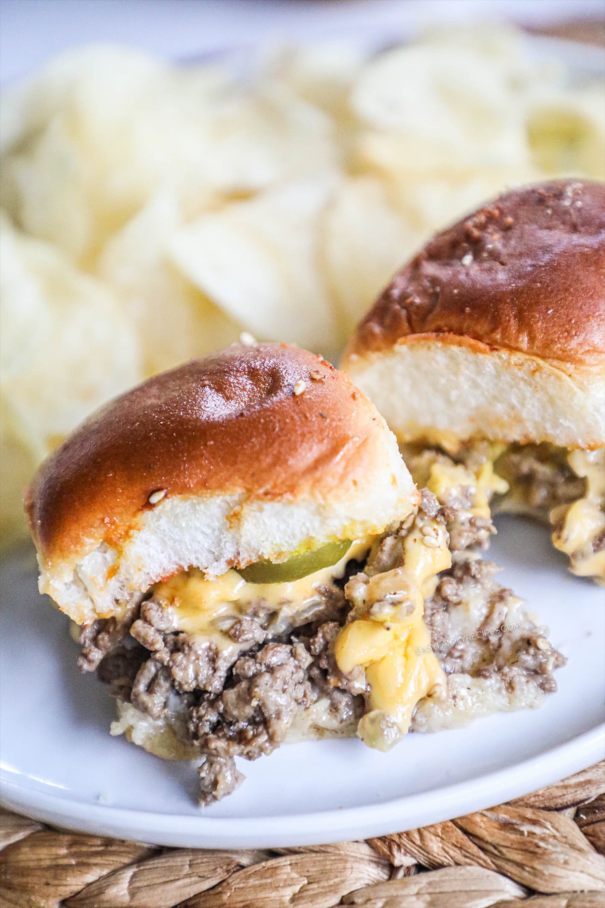 Close up of Hawaiian Roll Cheeseburger sliders served on a plate with chips.