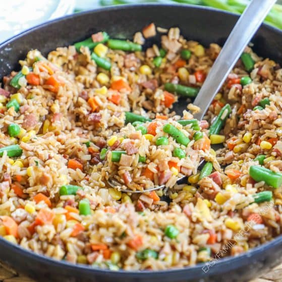 side view of a skillet full of fried rice with veggies and ham.