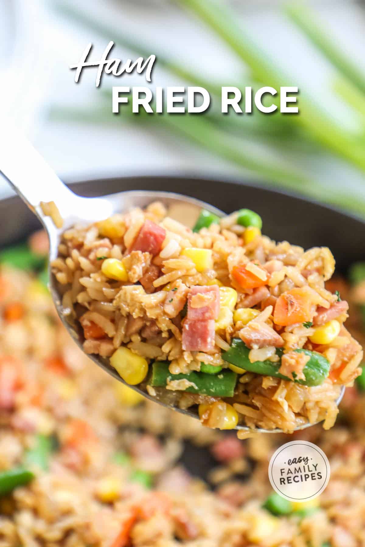 a spoonful of ham fried rice held over a skillet.