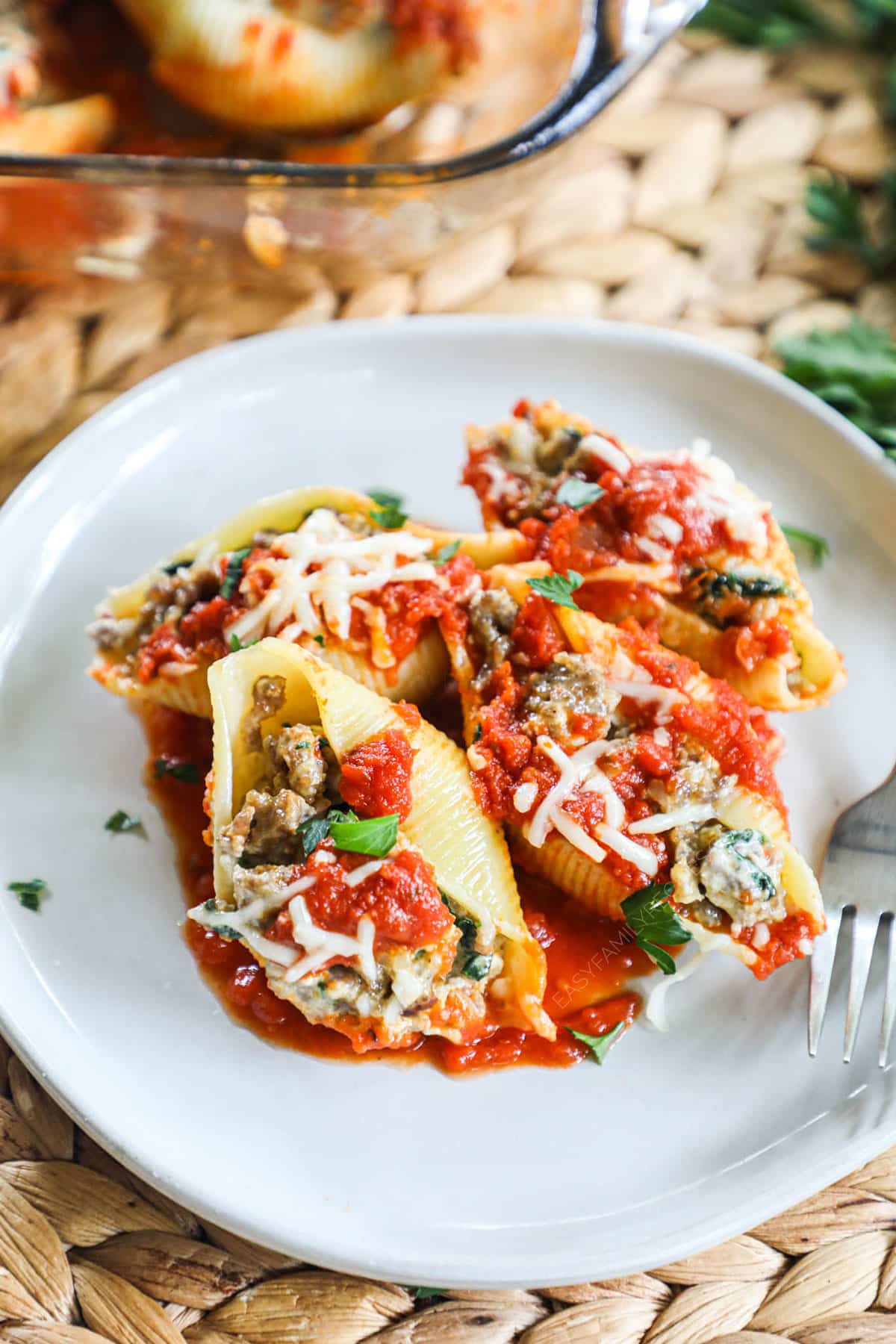 A plate full of pasta shells stuffed with meat and topped with marinara and mozzarella cheese.