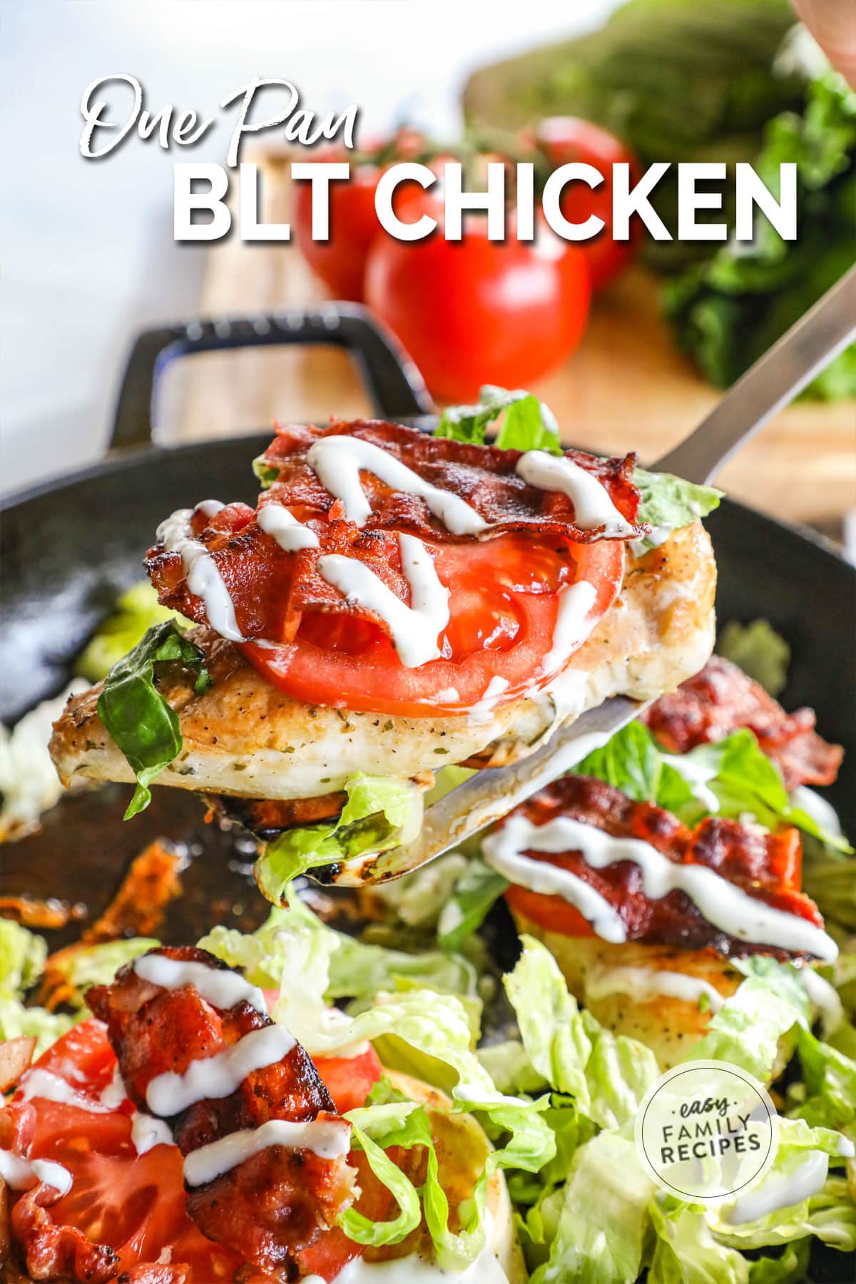 a chicken breast topped with lettuce, tomato, and ranch being lifted out of a skillet with a spatula.