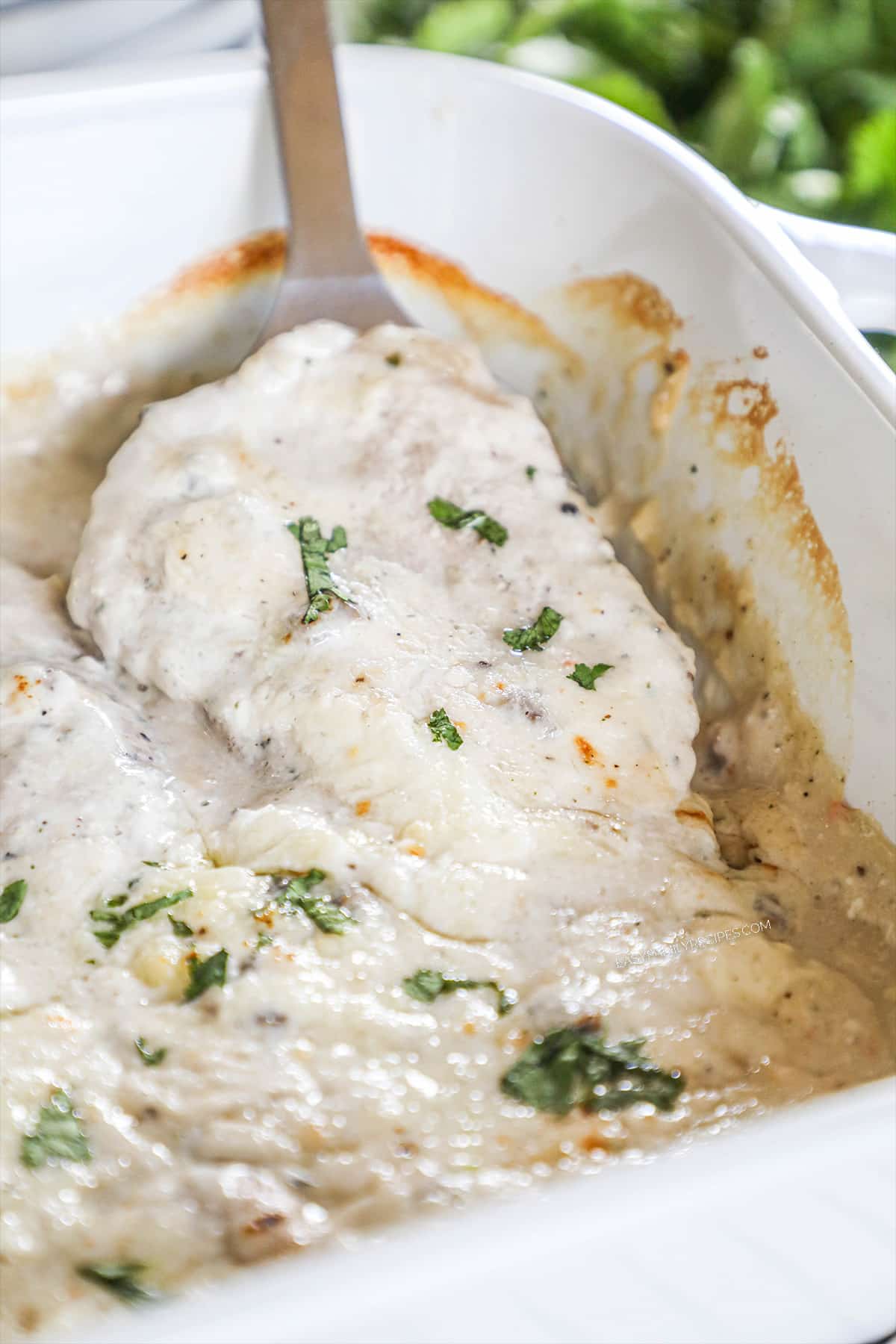 Spatula lifting cream of mushroom pork chops out of casserole dish.