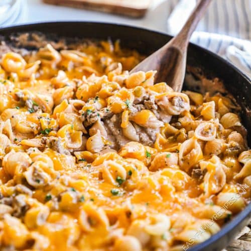 Cheesy beef and shells in a pot with a spoonful being scooped out.