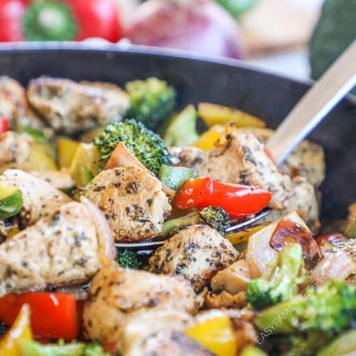 close up image of spoon scooping out chicken, peppers and broccoli