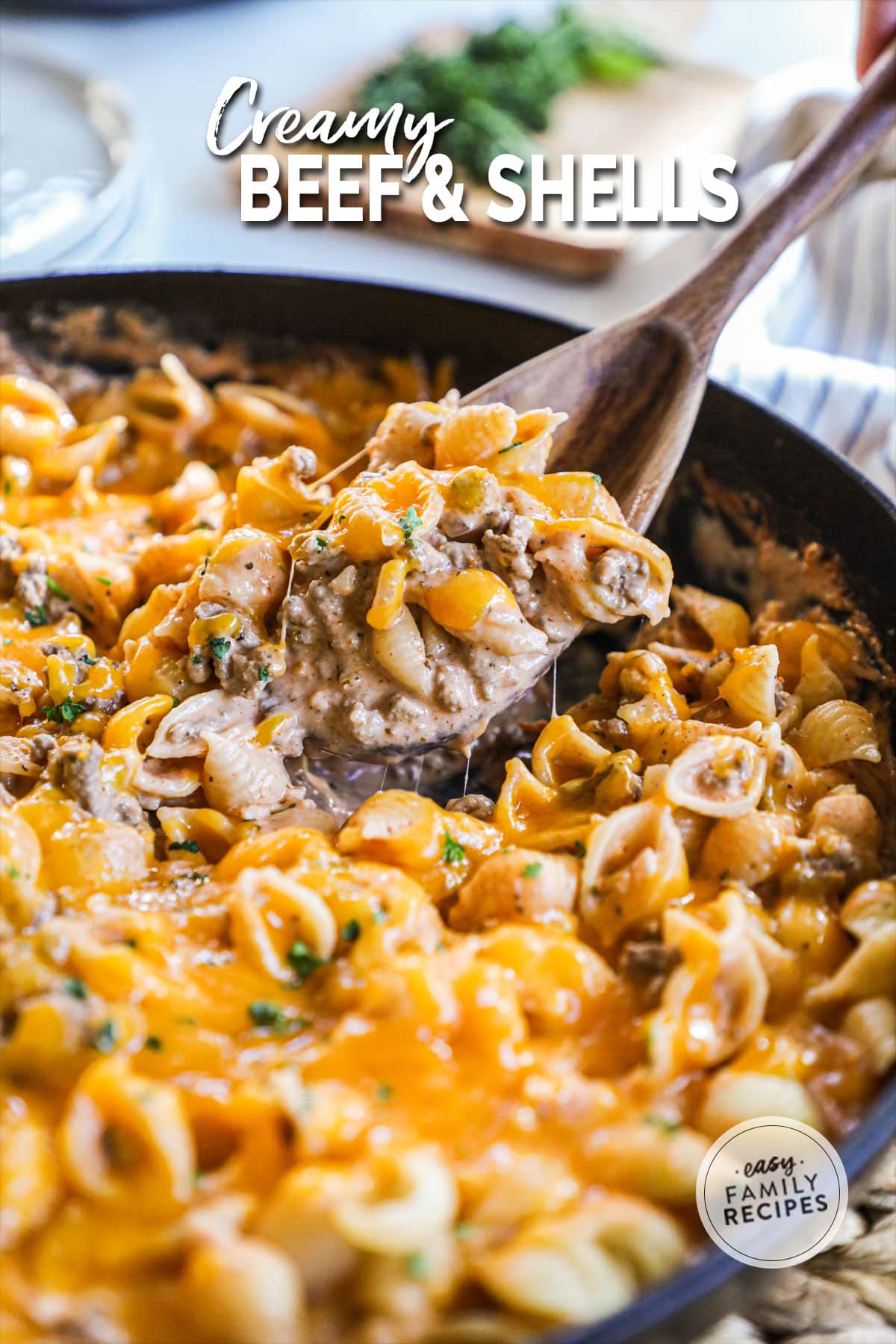 Cheesy beef and shells in a pot with a spoonful being scooped out.