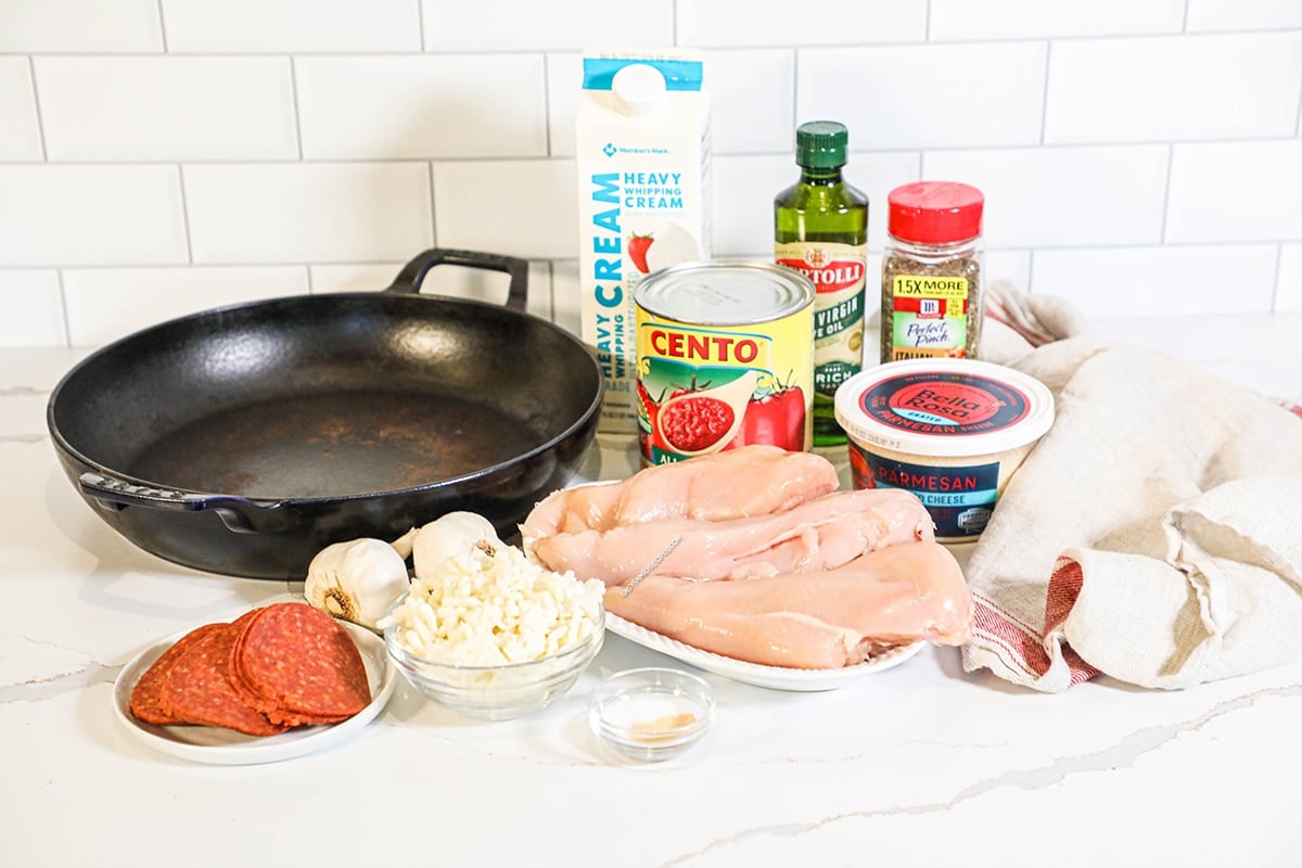 Ingredients for chicken pizzaiola, including chicken breasts, pepperoni, mozzarella, parmesan, garlic, crushed tomatoes, and more