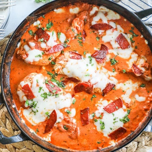 chicken breasts cooked in a skillet with tomato sauce and pepperoni pieces