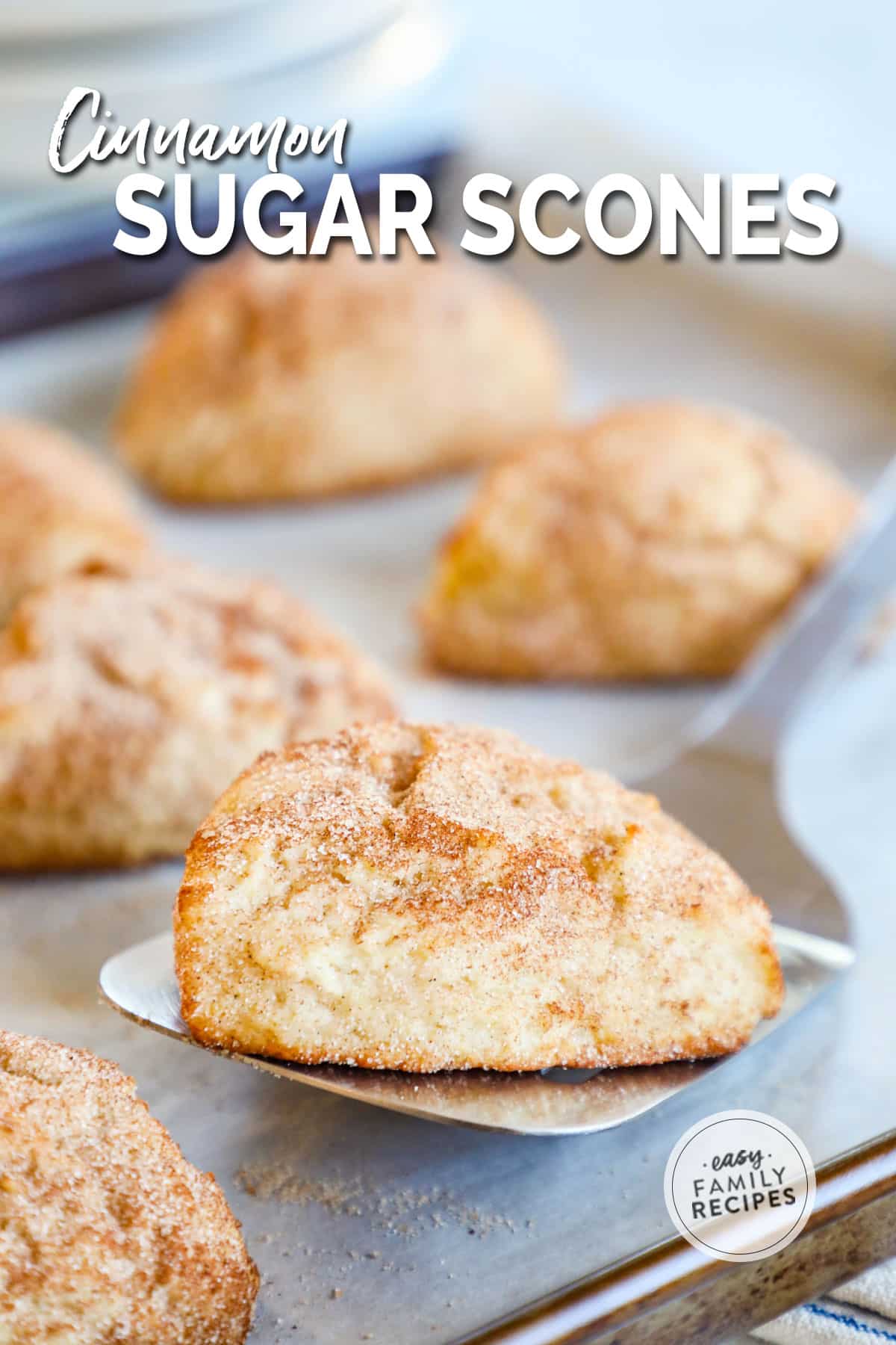 a spatula being used to lift a scone off of a baking sheet with more scones.