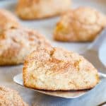 side view of a scone being lifted off of a baking sheet with a spatula.