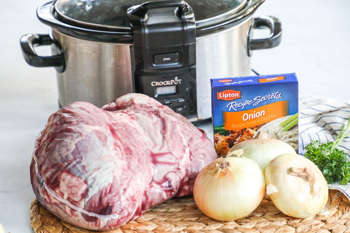 Slow cooker and ingredients for crockpot sirloin tip roast, including meat, onions, and onion soup