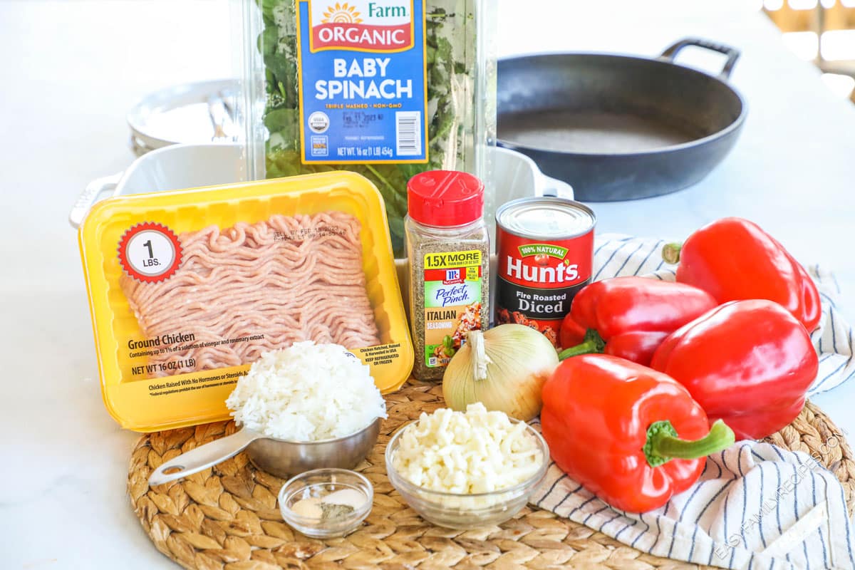 Ingredients for ground chicken stuffed peppers including spinach, rice, cheese, ground chicken, bell peppers, onion, and more