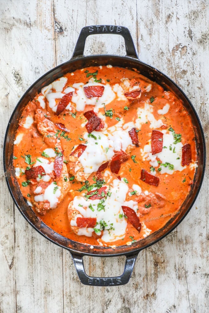 chicken breasts cooked in a skillet with tomato sauce and pepperoni pieces