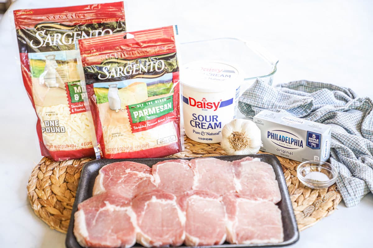 Ingredients to make pork chops including boneless pork chops, mozzarella, parmesan, sour cream, cream cheese, garlic, and salt and pepper.