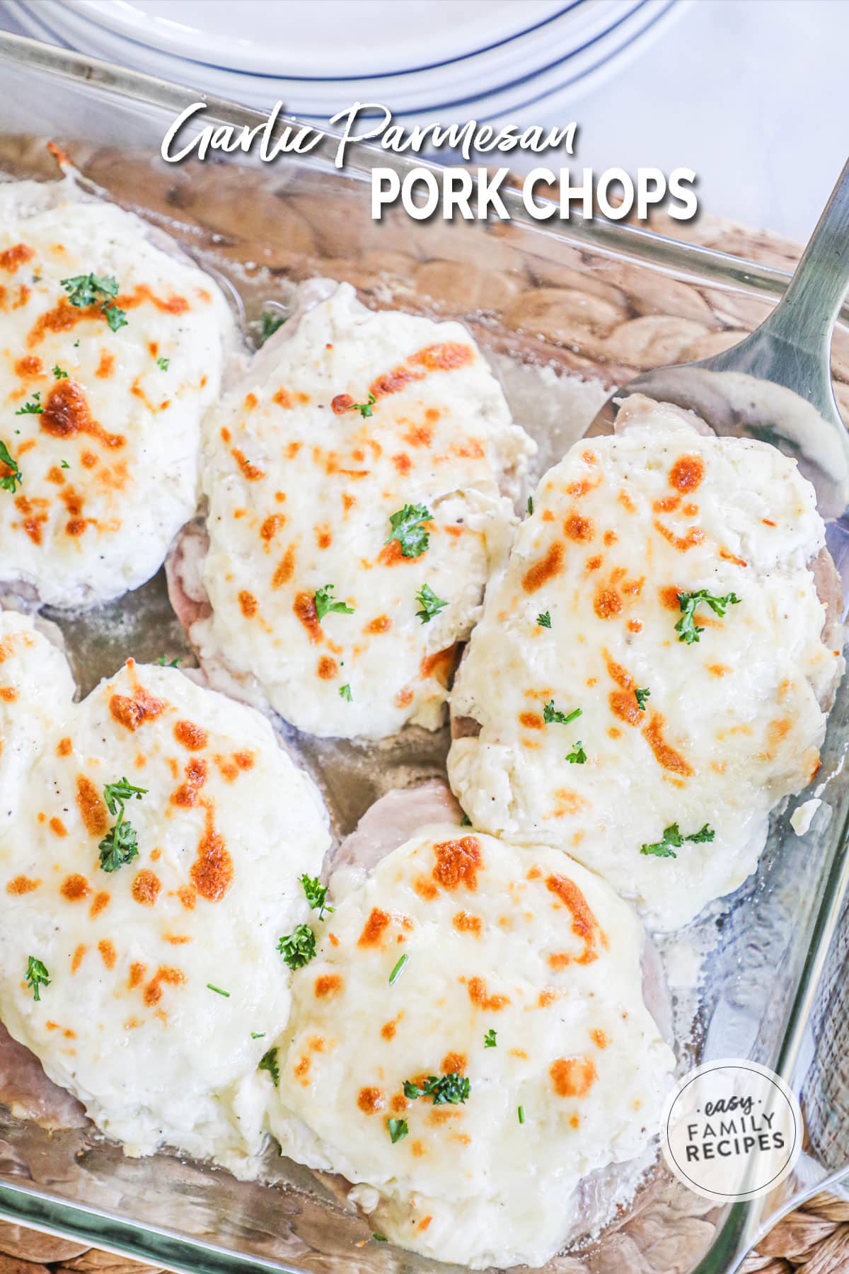 Pork chops covered in cheese sauce that is golden brown and topped with parsley.