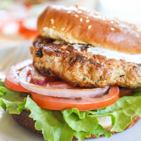 Buffalo chicken burger on plate, with ranch, lettuce, tomato, and onion