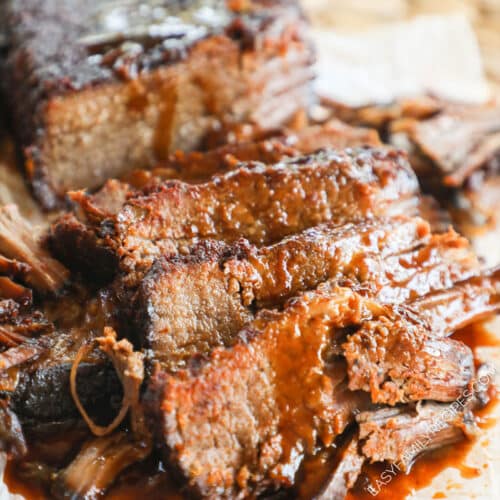 Brisket cooked in slow cooker taken out and sliced with BBQ sauce