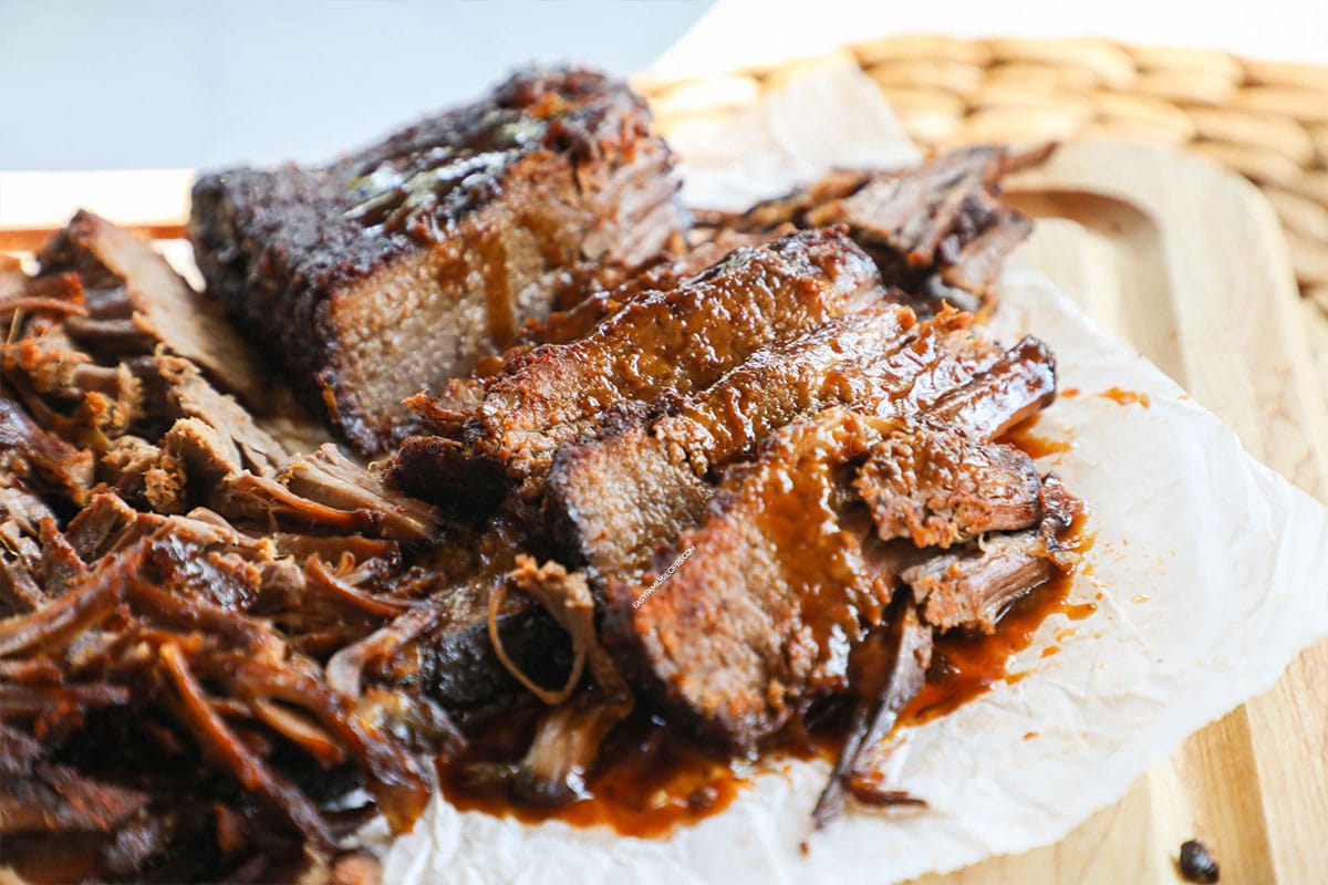 Brisket cooked in slow cooker taken out and sliced with BBQ sauce