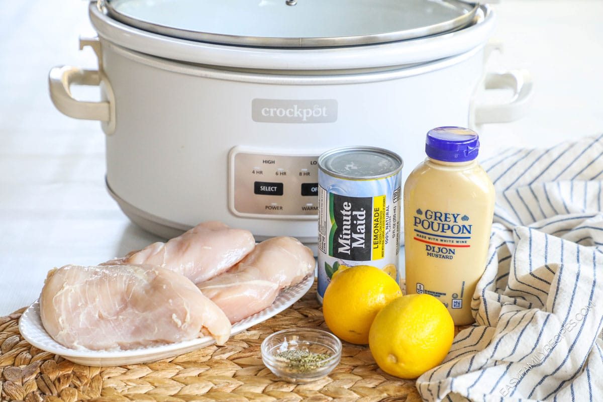Ingredients for crockpot lemonade chicken, including chicken breasts, lemonade concentrate, lemons, mustard, and seasonings
