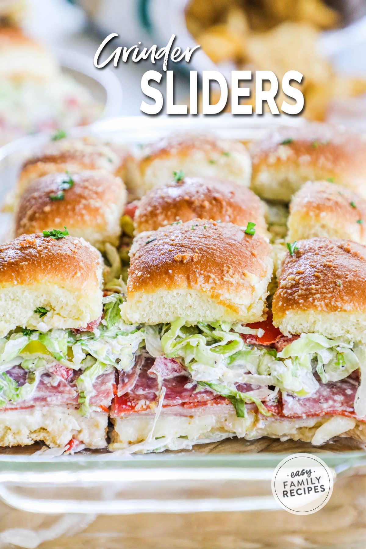Italian grinder sliders layered with cheese, deli meat, and a dressed shredded salad with crisp top buns.