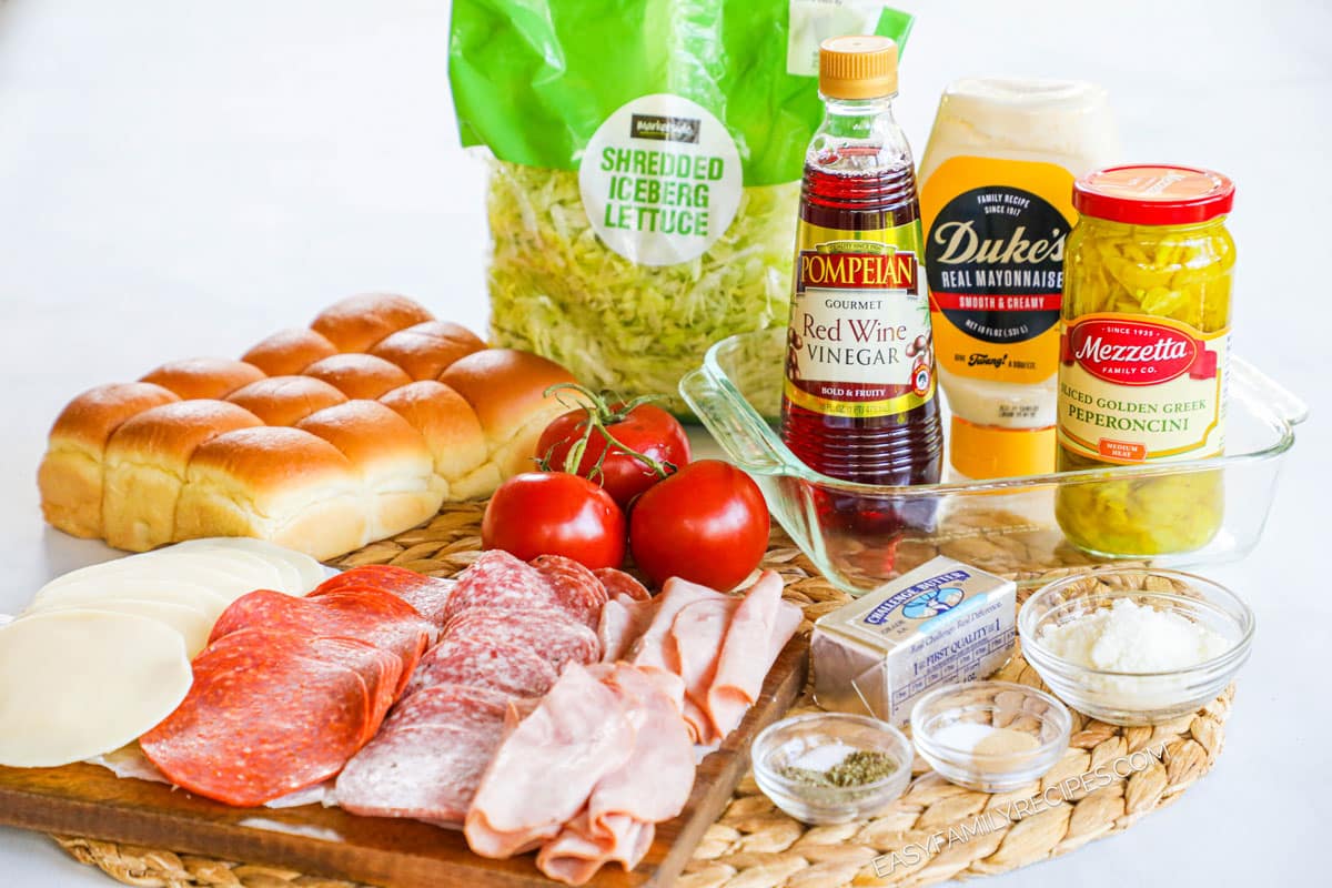 Ingredients for recipe: Hawaiian rolls, sliced deli meats and provolone cheese, tomato, shredded lettuce, red wine vinegar, mayo, pepperoncini, butter, spices, and parmesan cheese.