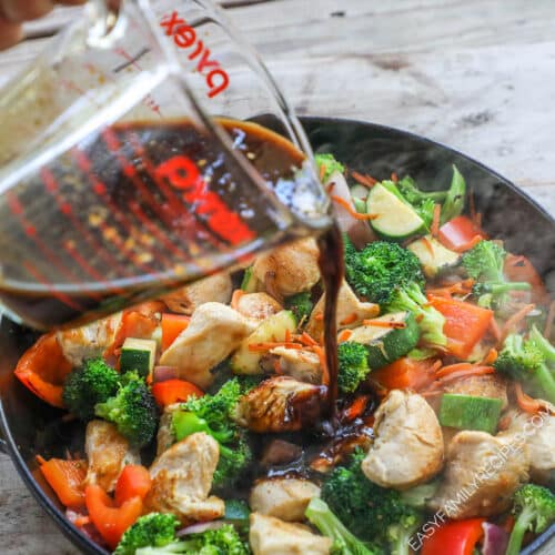 Stir Fry sauce recipe being poured over chicken and vegetables in hot pan.