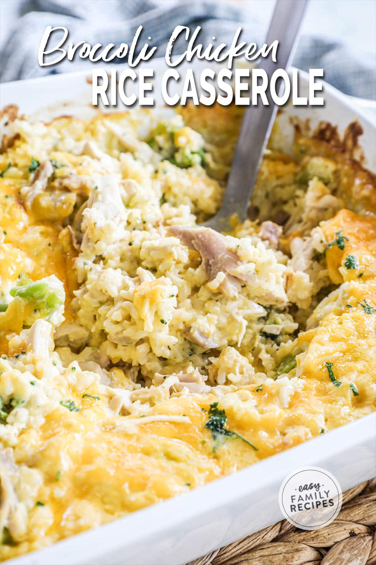 Close up of broccoli chicken rice casserole in a baking dish with a serving spoon dipped into it.