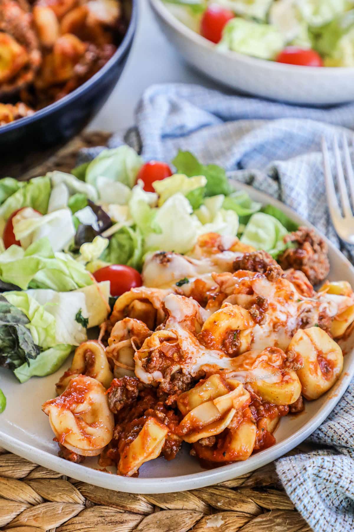 Baked Tortellini Casserole served with salad on a plate.