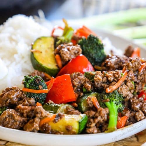 a plate with white rice beside ground beef and vegetable stir fry.