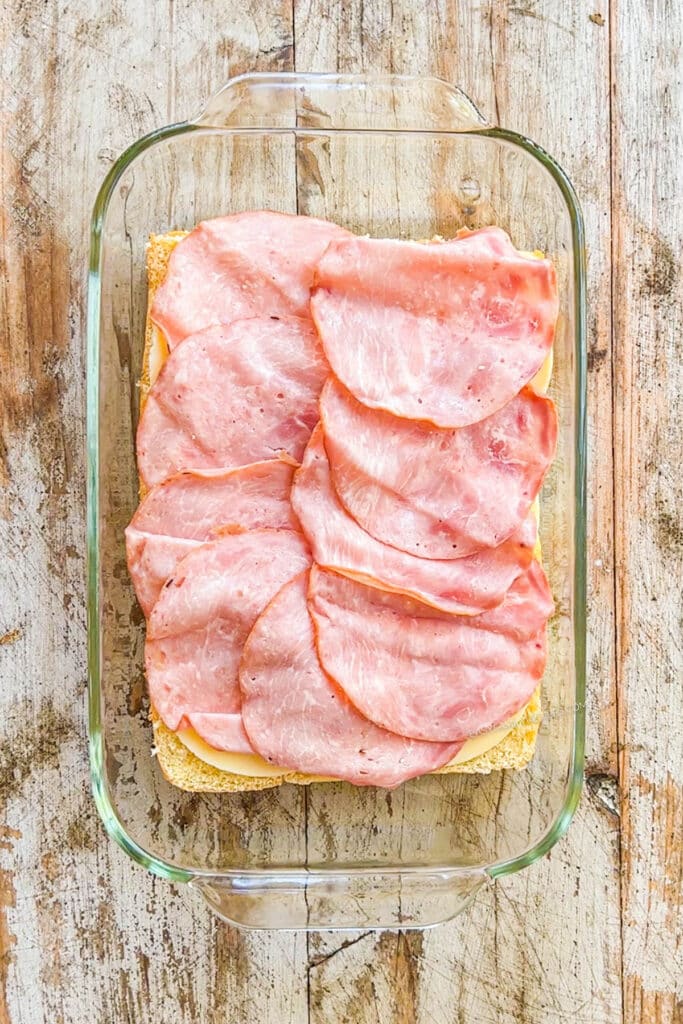 How to make Italian Grinder Sliders Step 1: Place the bottom of the hawaiian rolls in the pan and top with ham.