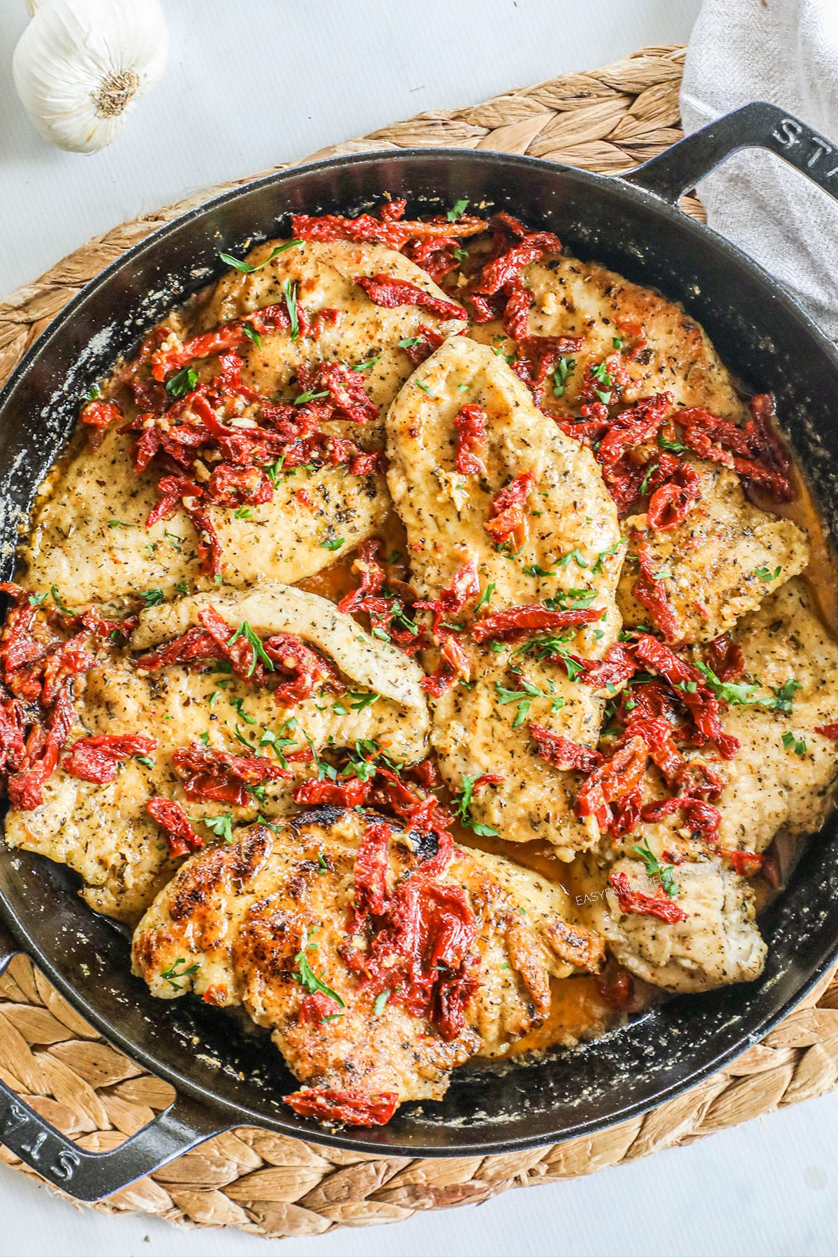 Picture has a pan full of marry chicken with a creamy sauce and sun-dried tomatoes and basil.