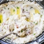 overhead of garlic mashed potatoes in a slow cooker with a spoon.