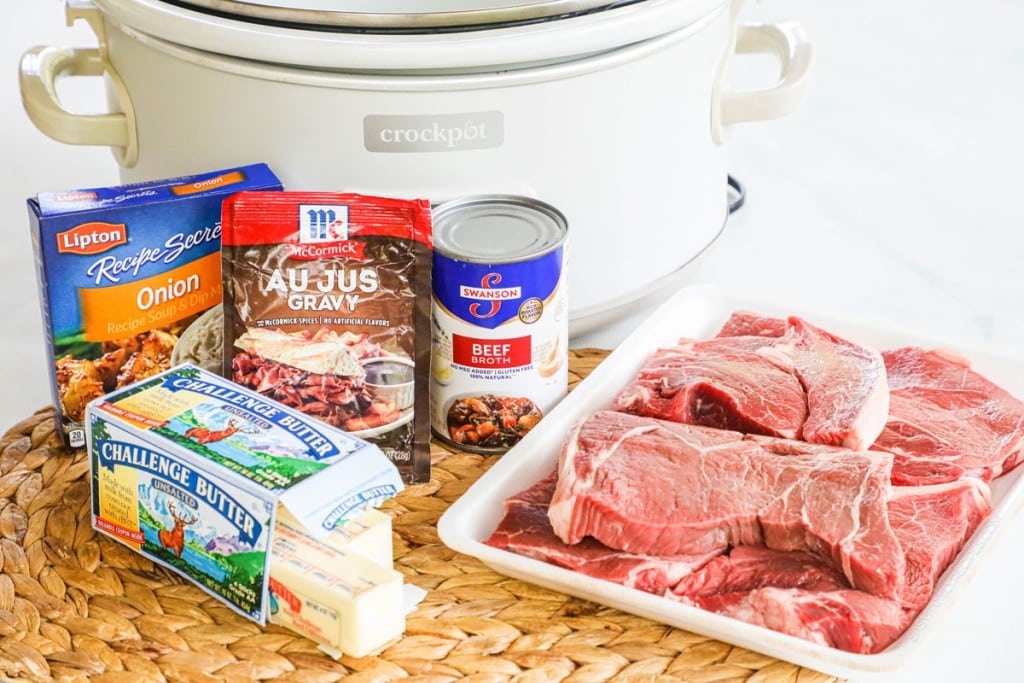 Ingredients for crockpot steak bites, including steak, butter, beef broth, and seasonings