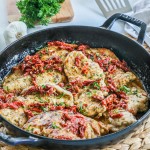 Picture has a pan full of marry chicken with a creamy sauce and sun-dried tomatoes and basil.