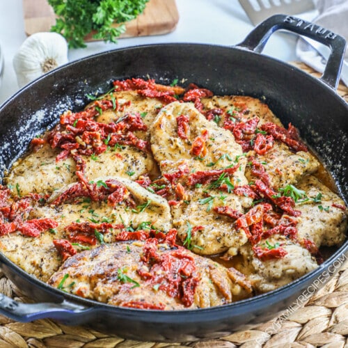 Picture has a pan full of marry chicken with a creamy sauce and sun-dried tomatoes and basil.