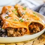 Two beef enchiladas on plate with black beans