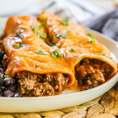 Two beef enchiladas on plate with black beans