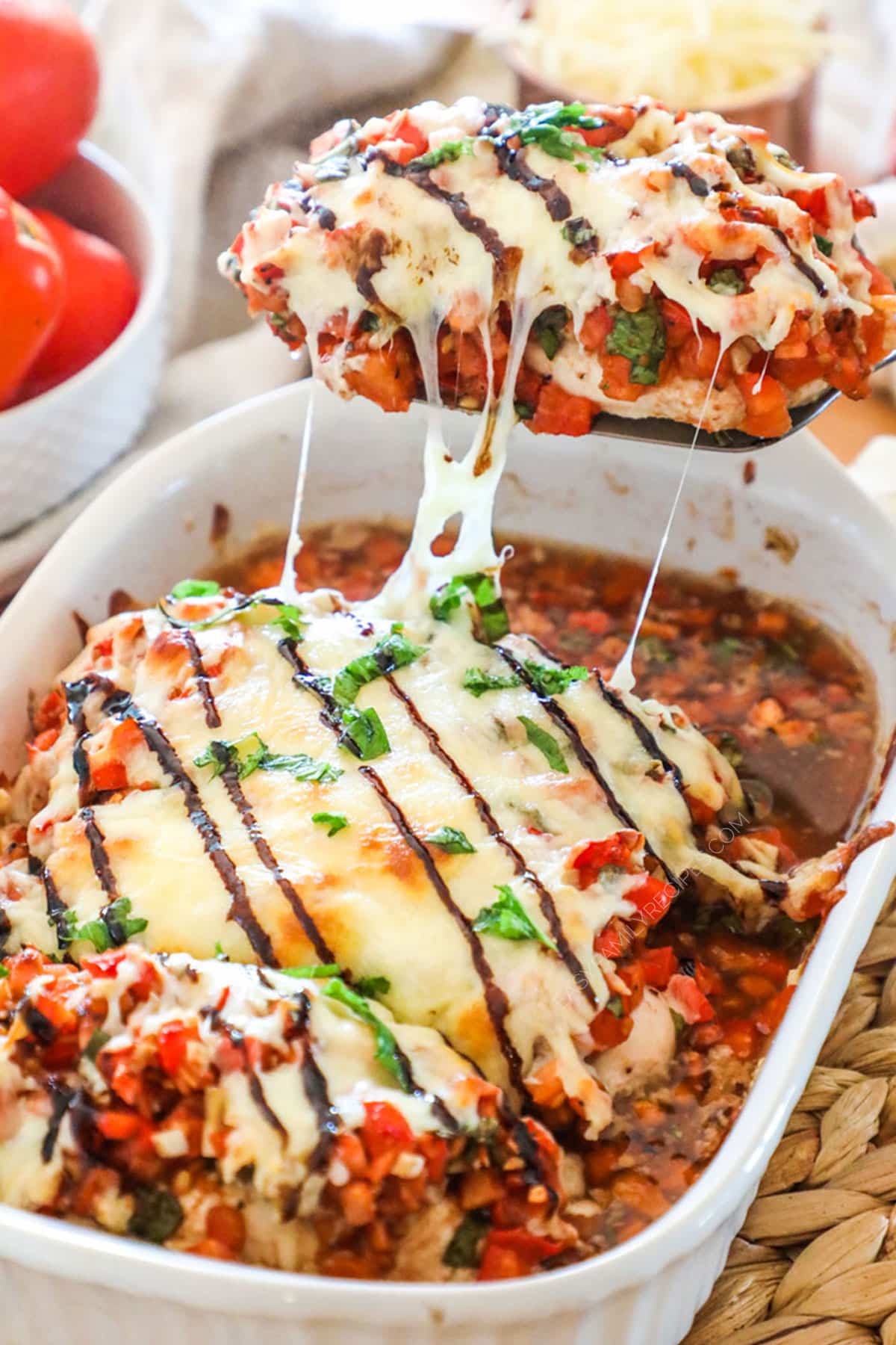 Chicken Bruschetta in a casserole dish being scooped out.