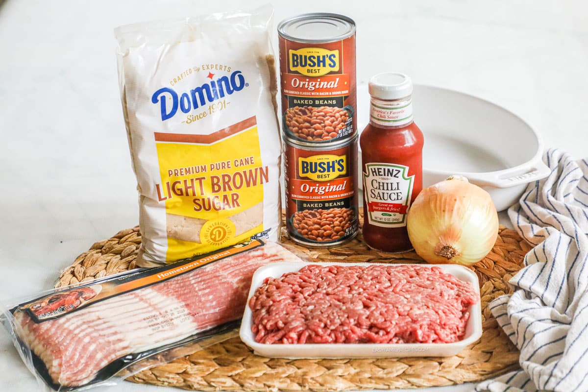Ingredients for cowboy baked beans, including ground beef, bacon, onion, chili sauce, baked beans, brown sugar