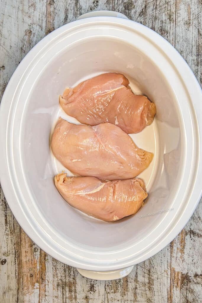 How to make crockpot BBQ Chicken step 1: Lay the chicken in the bottom of the crockpot.