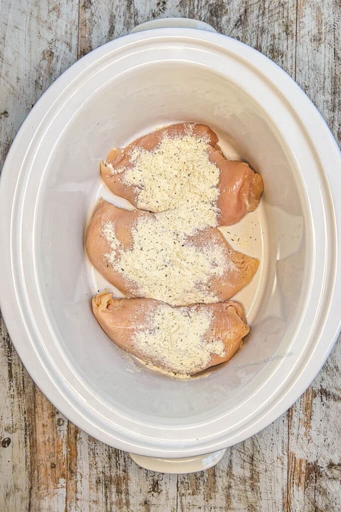 How to make crockpot BBQ Chicken step 2:Cover chicken with ranch seasoning on both sides. Pour the BBQ sauce over the top of the chicken to cover.